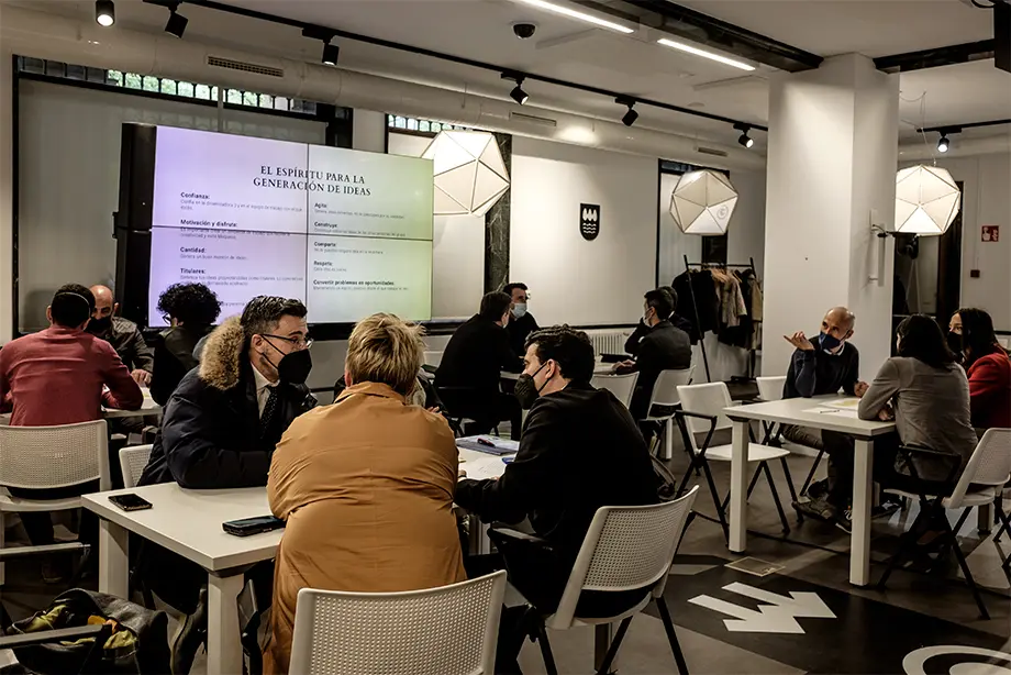 Imagen en la que se ve a las personas sentadas y empezando a trabajar en las diferentes mesas de trabajo